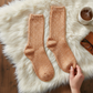 Mellow Monkey orange slub marbled crew socks with a ribbed texture resting on a soft white faux fur rug.