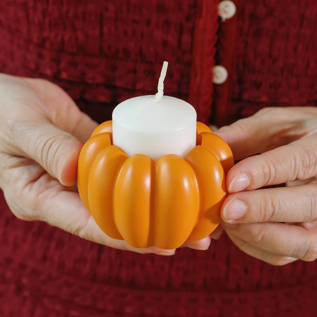 Mellow Monkey orange resin pumpkin tealight holder held in hands with a white candle insert for fall home decor