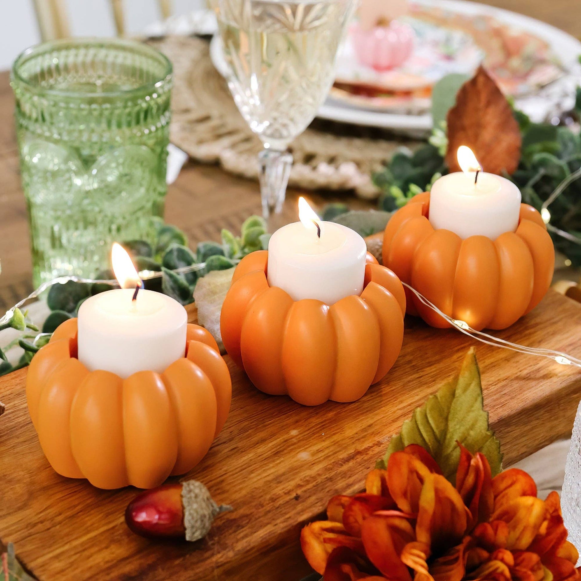 Mellow Monkey set of three orange resin pumpkin tealight holders on a wooden table with autumn decor