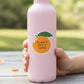 Mellow Monkey Aren't You A Cutie vinyl orange sticker on a light pink water bottle held by a hand outdoors