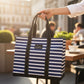 Mellow Monkey Original Deano large tote bag in navy and white stripes held by a hand at an outdoor cafe