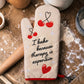 Mellow Monkey cream oven mitt with red trim, featuring cherries and the text "I bake because therapy is expensive."