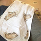 Mellow Monkey oyster print 2-in-1 bamboo and cotton muslin burp cloth and baby bib draped over a shoulder