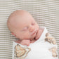 Mellow Monkey baby swaddled in a soft white muslin blanket featuring an oyster shell print