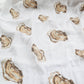 Mellow Monkey white muslin baby swaddle blanket featuring a repeating brown and tan oyster shell pattern.
