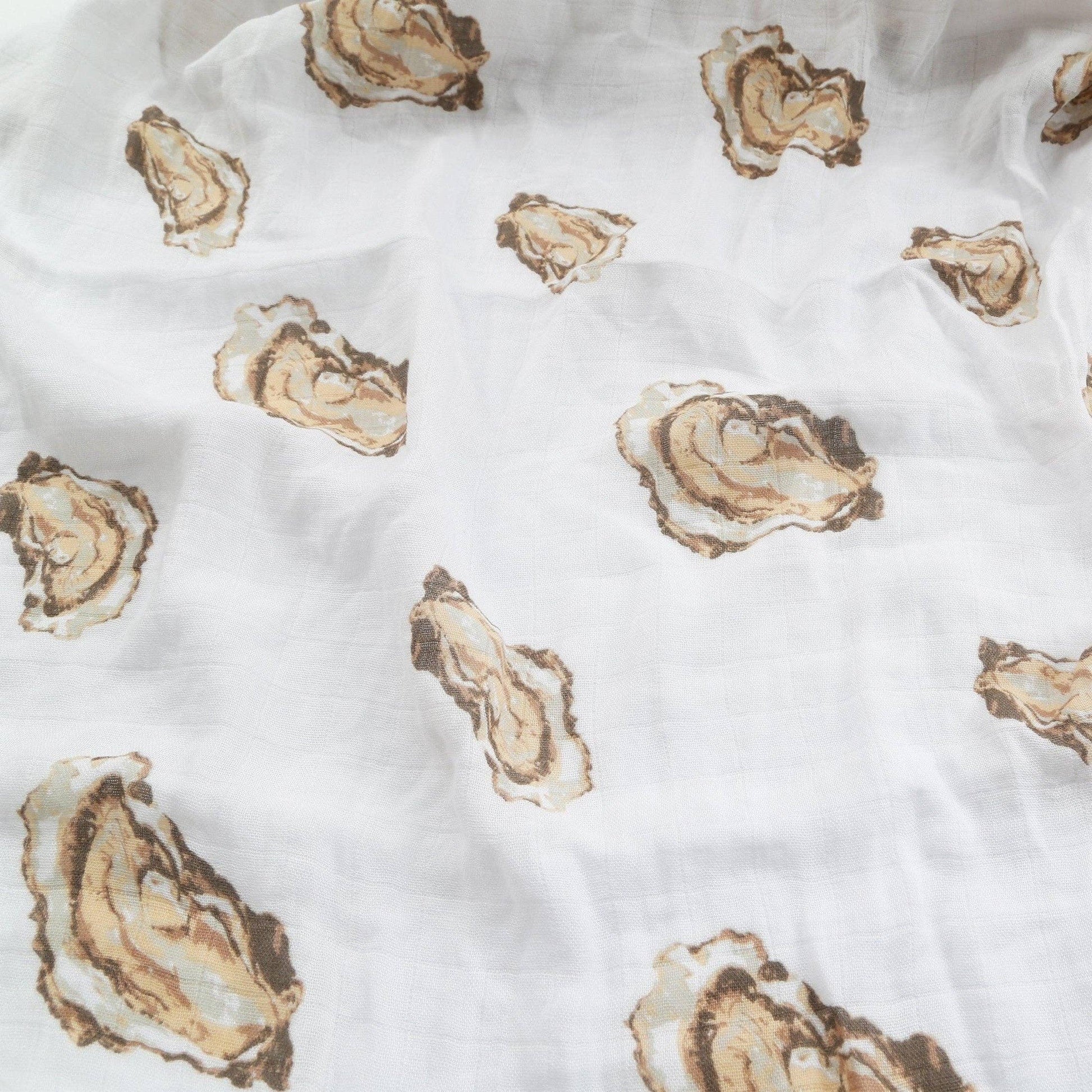 Mellow Monkey white muslin baby swaddle blanket featuring a repeating brown and tan oyster shell pattern.