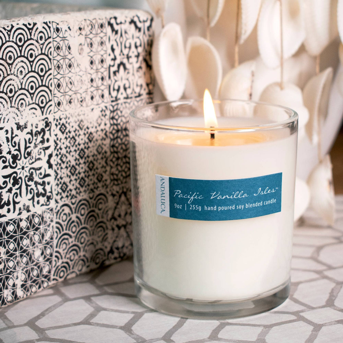Mellow Monkey 9-oz Pacific Vanilla Isles soy blend candle in a glass jar with a lit wick on a patterned surface.