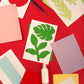 Mellow Monkey Crafters Paper Flowers Kit with colorful paper sheets, green leaf stencils, glue, and a paintbrush.