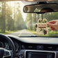 Mellow Monkey paw-shaped Evergreen Forest car air freshener hanging in a car with a scenic forest road view