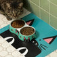 Mellow Monkey Peeking Kitty Double Pet Bowl with stainless steel inserts, teal base with cat face design, holding kibble and water.