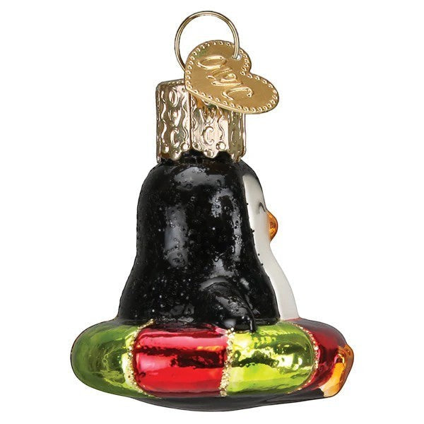 Mellow Monkey Mini Penguin Old World Christmas blown glass ornament, black and white with orange beak, on a red and green float.