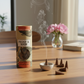 Mellow Monkey peony and suede scented incense cones with a small ceramic holder and smoking cone on a wooden table.