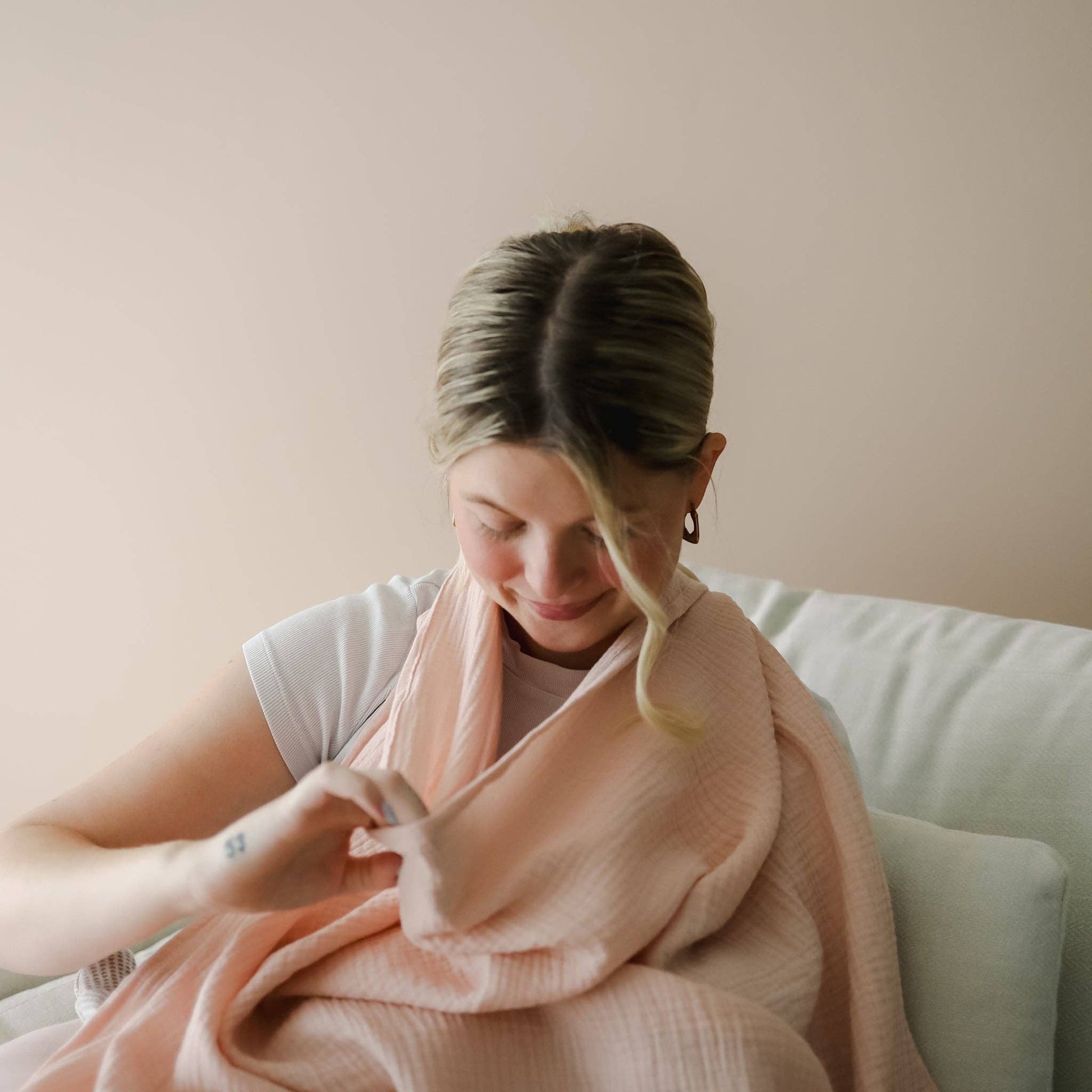 Mellow Monkey Petal nursing cover in soft pink organic cotton muslin with a built-in silicone teether ring.
