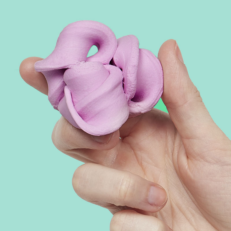 Mellow Monkey Speks Blur Focus Putty in petal pink being held in a hand against a light green background