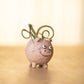 Mellow Monkey Henrietta the Pig Blobhouse Planter, a pink handcrafted poly-resin planter with googly eyes and a smiling face, holding a small plant.
