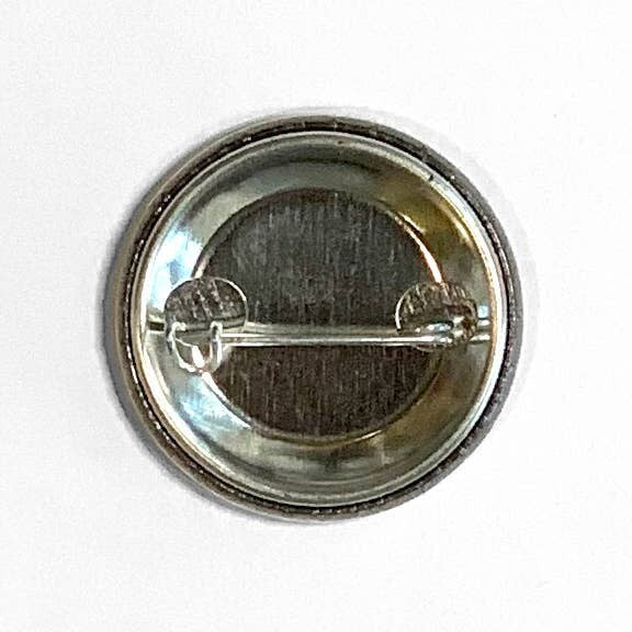 Back view of a 1.25 inch Mellow Monkey pin-back button showing the metal shell and clasped pin mechanism.