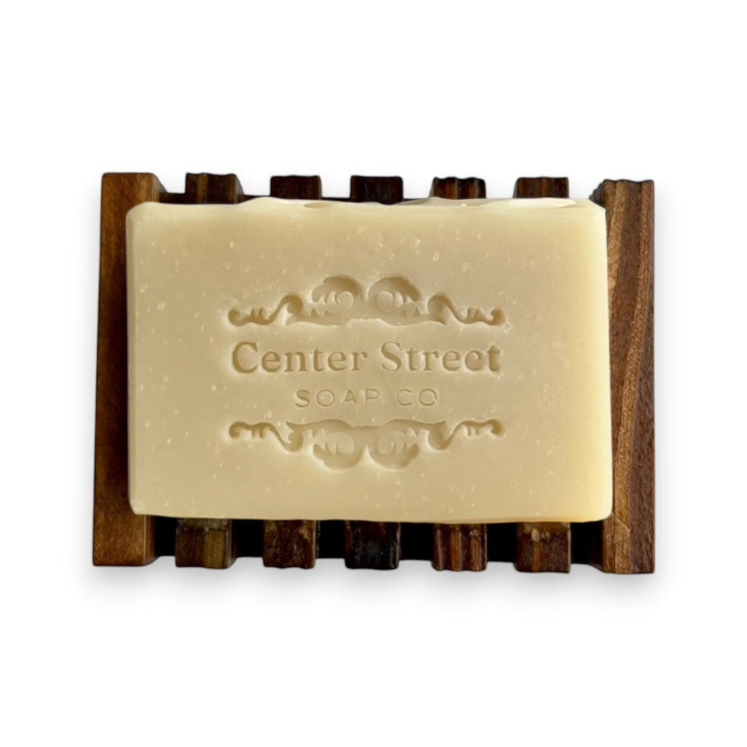 Mellow Monkey natural pine wood soap dish with self-draining slats holding a bar of soap.