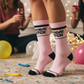 Mellow Monkey pink mid-calf gym crew socks with Birthday Bitch text, worn at a birthday party celebration.