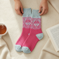 Mellow Monkey pink and blue confetti holiday crew socks with snowflake pattern held by hands on a cozy blanket