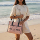 Mellow Monkey pink Sel de Mer canvas tote bag with leather handles and shoulder strap held by a woman on the beach.