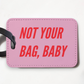 Mellow Monkey pink faux leather luggage tag with Not Your Bag Baby text in red and a black plastic strap