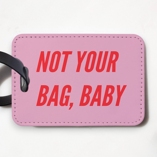Mellow Monkey pink faux leather luggage tag with Not Your Bag Baby text in red and a black plastic strap