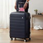 Mellow Monkey pink faux leather luggage tag with Not Your Bag Baby text attached to a dark blue suitcase