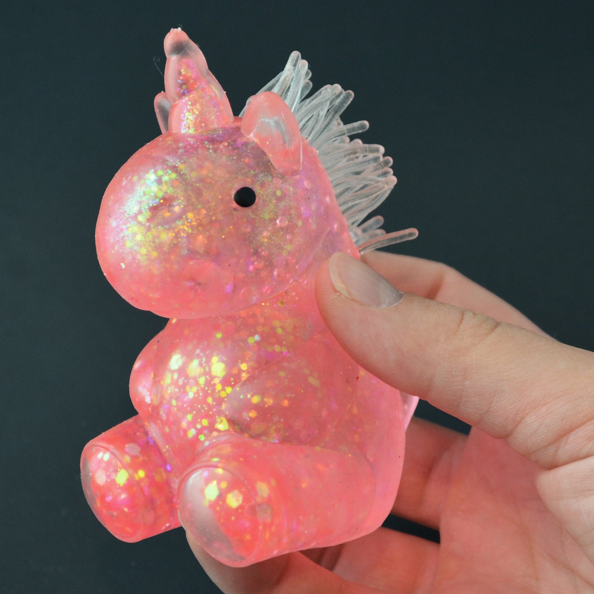 Mellow Monkey pink glittery unicorn squishy toy held in a hand for stress relief and sensory play.