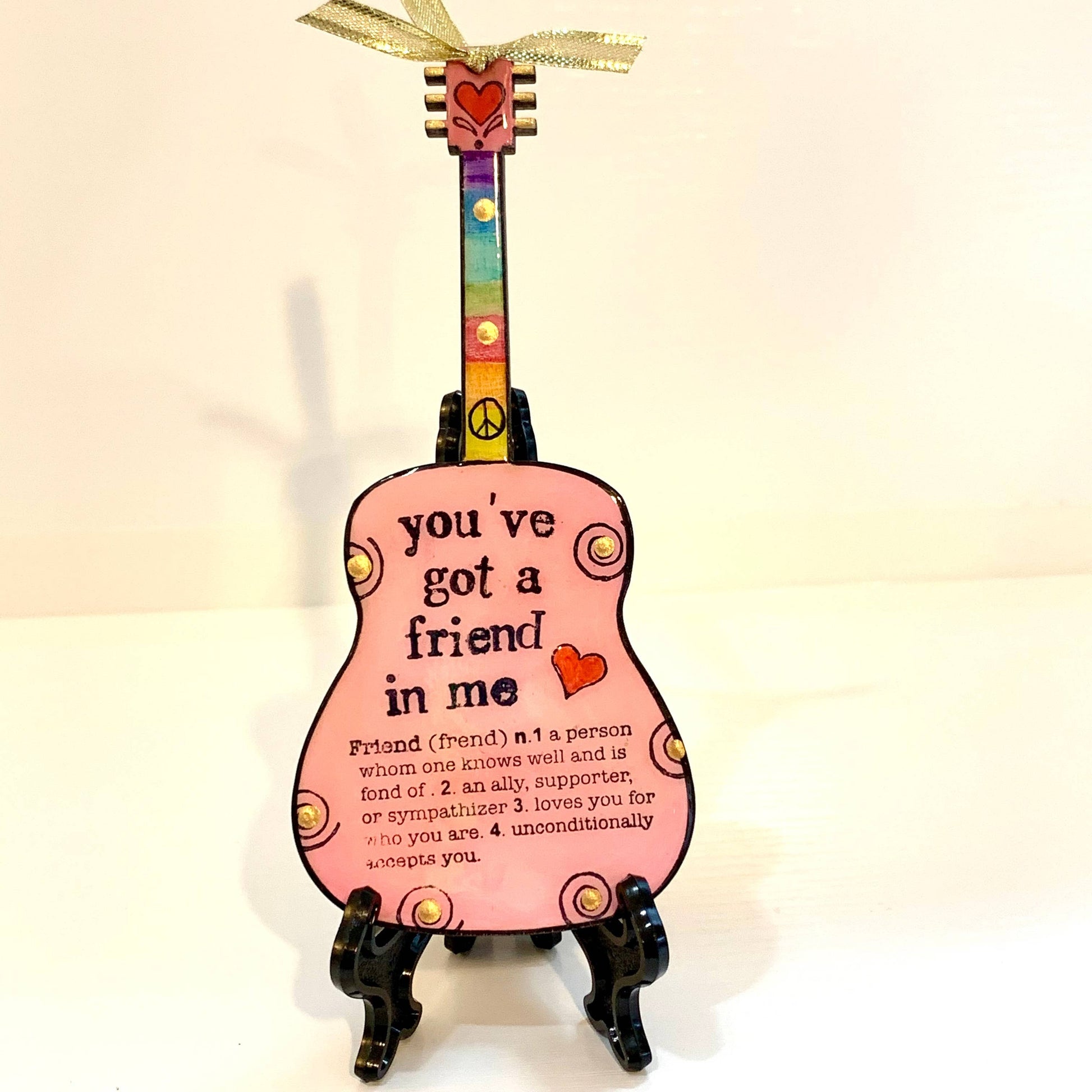 Mellow Monkey pink guitar ornament featuring You've Got A Friend in Me text, rainbow neck, and gold ribbon display.