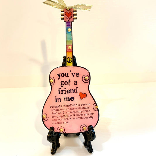 Mellow Monkey pink guitar ornament featuring You've Got A Friend in Me text, rainbow neck, and gold ribbon display.