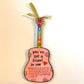 Mellow Monkey pink hand-painted guitar ornament with You've Got A Friend in Me text and gold ribbon hanger.