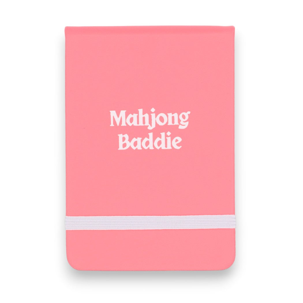 Mellow Monkey pink leatherette pocket journal with Mahjong Baddie embossed in white text and a white elastic band.