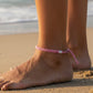 Mellow Monkey pink woven cotton nautical anklet worn on a person's ankle at the beach.