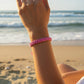 Mellow Monkey pink woven cotton nautical bracelet on a wrist at the beach