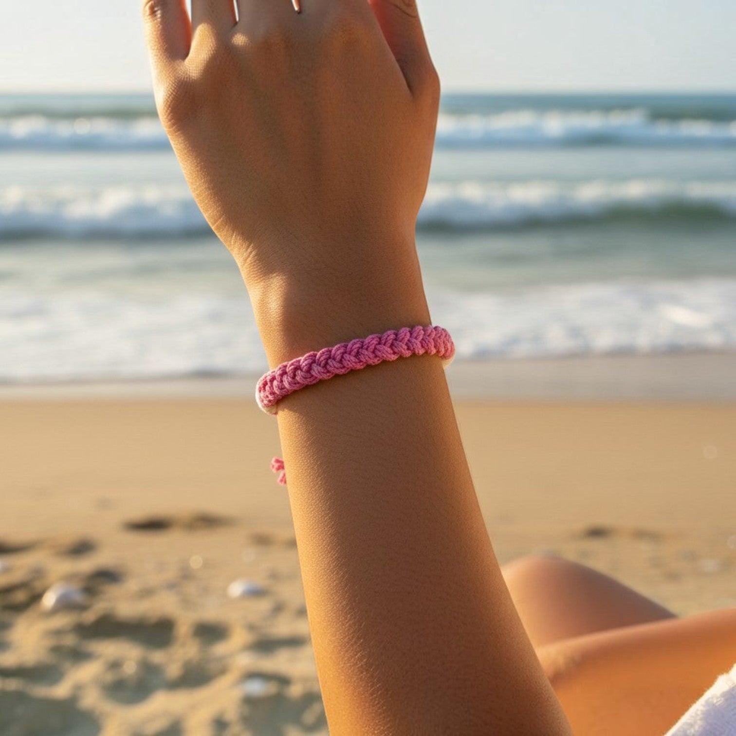 Mellow Monkey pink woven cotton nautical bracelet on a wrist at the beach