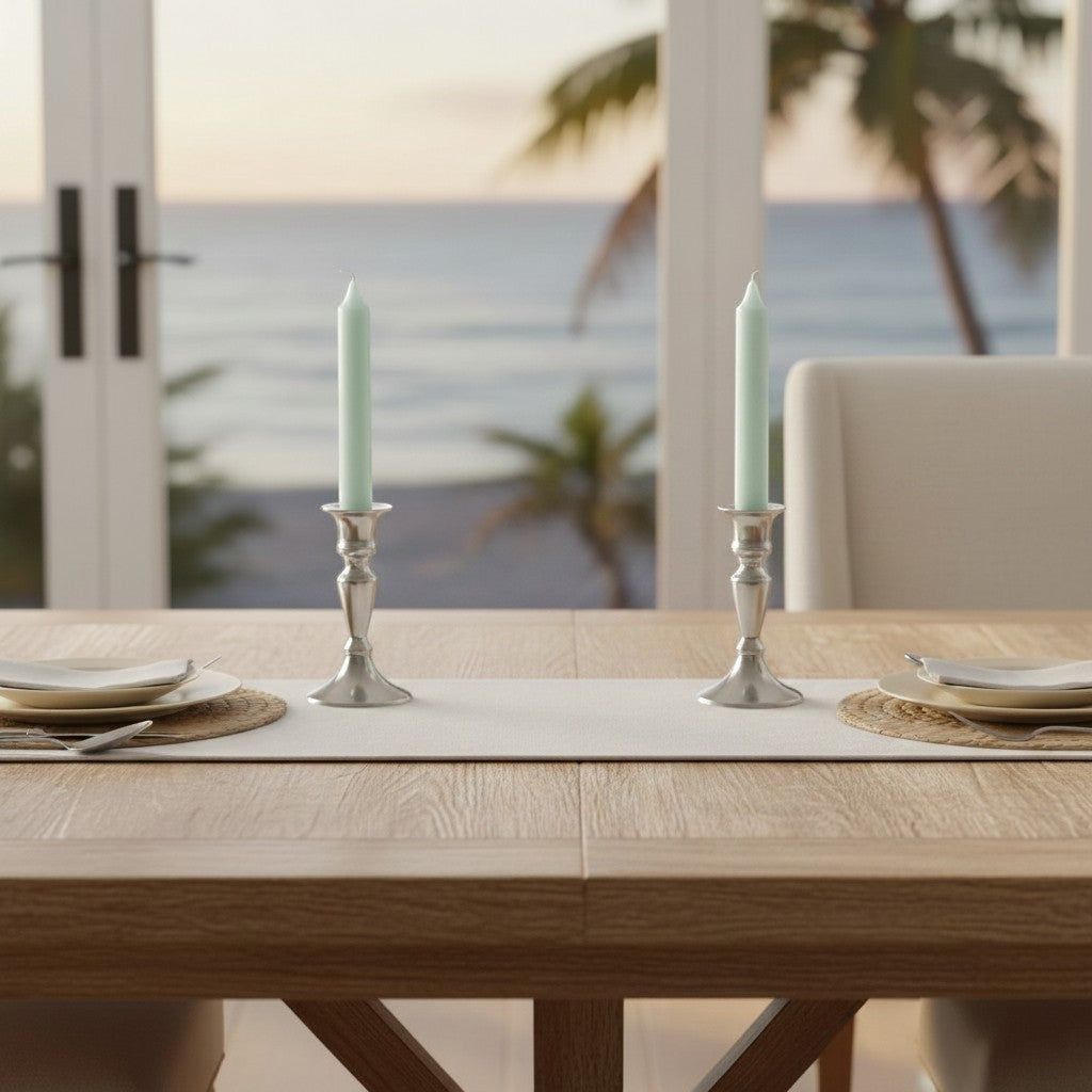 Mellow Monkey 7-inch pistachio taper candles in silver holders on a dining table with a beach view.