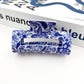 Mellow Monkey hair claw clip featuring a blue and white porcelain-inspired floral pattern on a white background.