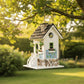 Mellow Monkey Primrose Cottage birdhouse with white exterior, black roof, green door and window trim, and floral motif.