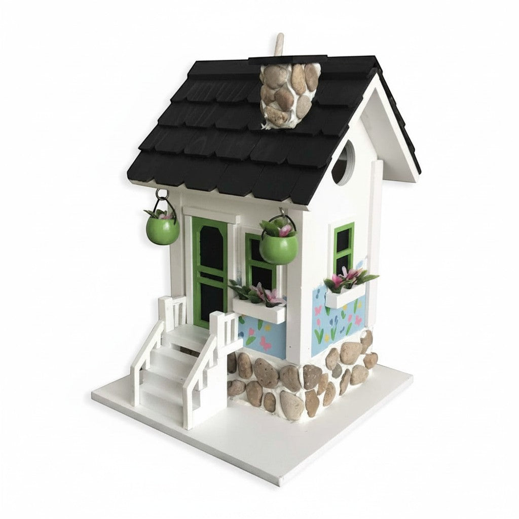 Mellow Monkey Primrose Cottage birdhouse with white exterior, black roof, green trim, and floral motif. Features river rock accents and hanging planters.