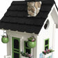 Mellow Monkey Primrose Cottage birdhouse with white exterior, black roof, green door and windows, and floral motif with river rocks.