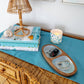 Mellow Monkey oval acacia wood serving tray featuring Kim Hovell Providence oyster shell artwork on a blue runner