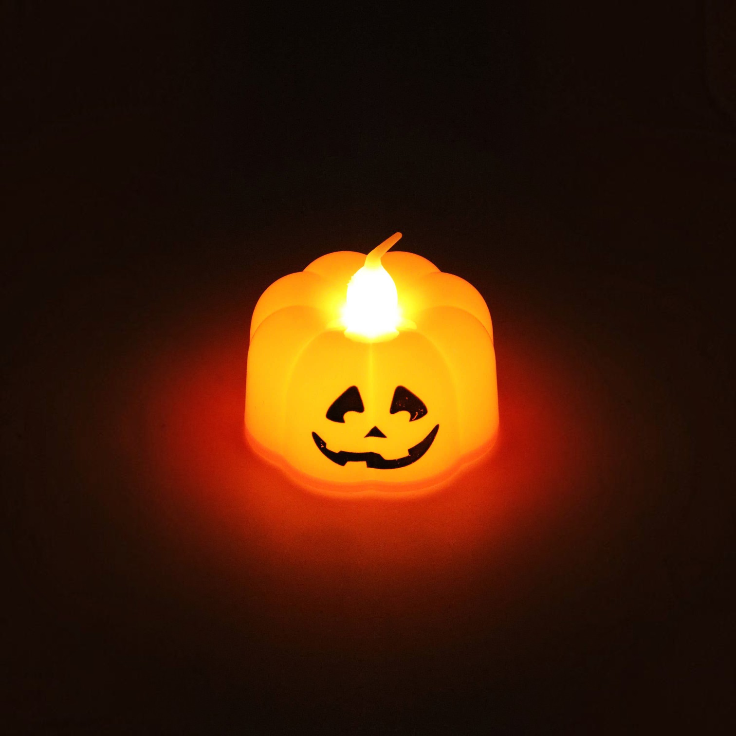 Mellow Monkey mini orange plastic pumpkin LED jack-o'-lantern tealight candle with a glowing warm light.