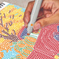 Mellow Monkey Pumpkins & Pastures FlowArt dot-by-letter activity pad with a hand using a marker to fill in dots.