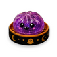 Mellow Monkey purple glittery squishy dumpling toy in a black Halloween-themed container with ghost and moon icons.