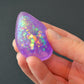 Mellow Monkey purple teardrop-shaped glittery squishy fidget toy held in a hand
