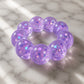 Mellow Monkey Purple Haze Feelzies sensory bracelet with purple glitter and flower confetti on marble surface.