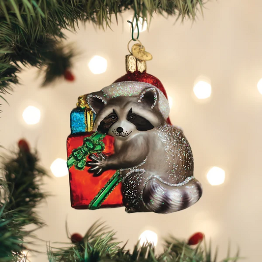 Mellow Monkey Jimothy raccoon Christmas ornament in blown glass, wearing a Santa hat and holding wrapped gifts.