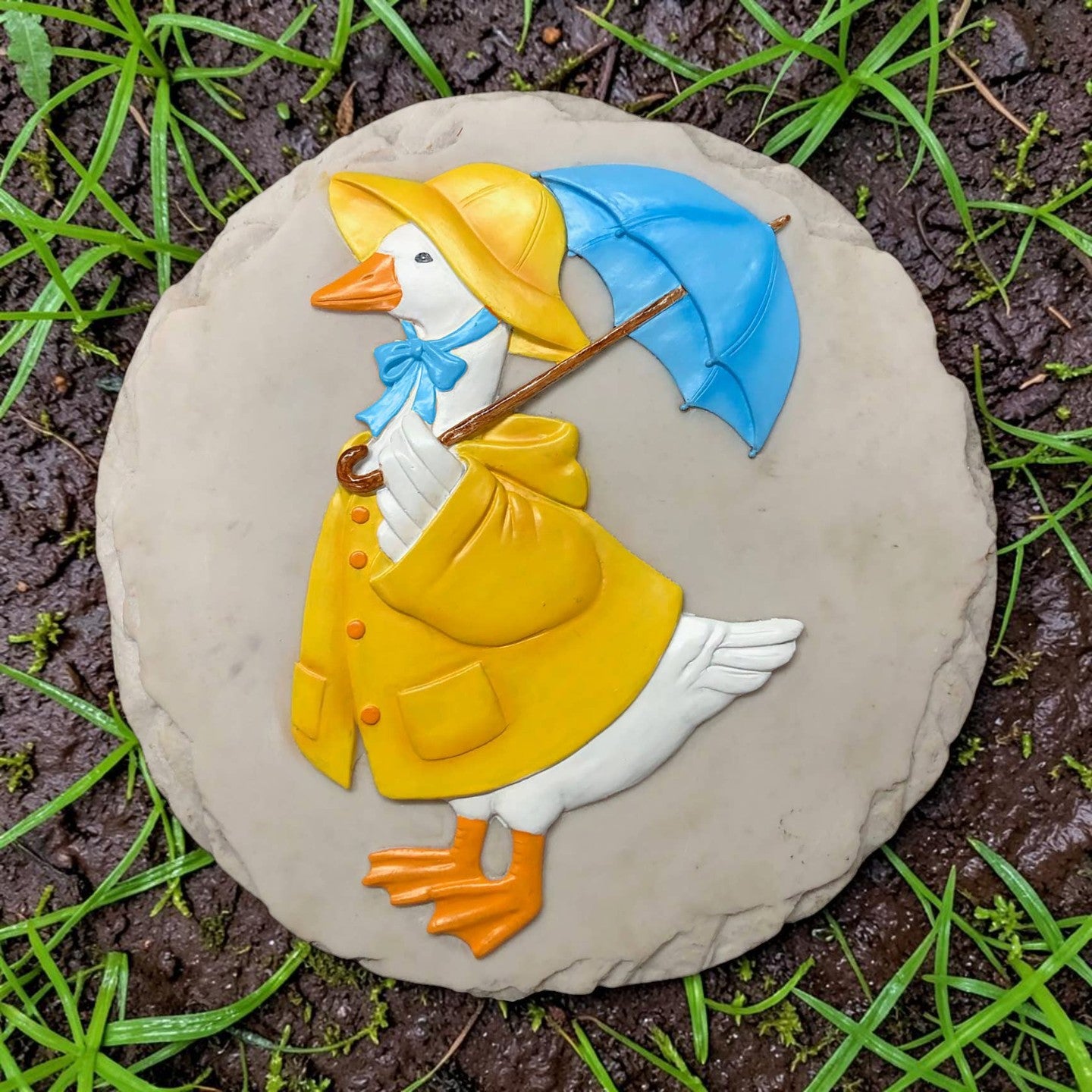 Mellow Monkey Rain Goose stepping stone featuring a white goose in a yellow raincoat and blue umbrella on stone base