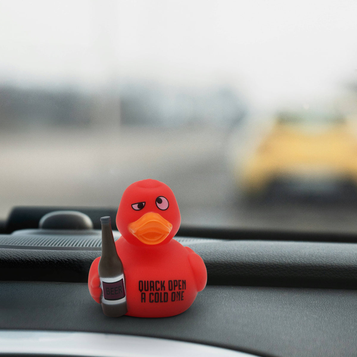 Mellow Monkey red rubber duck holding a beer bottle with Quack Open a Cold One text on a car dashboard