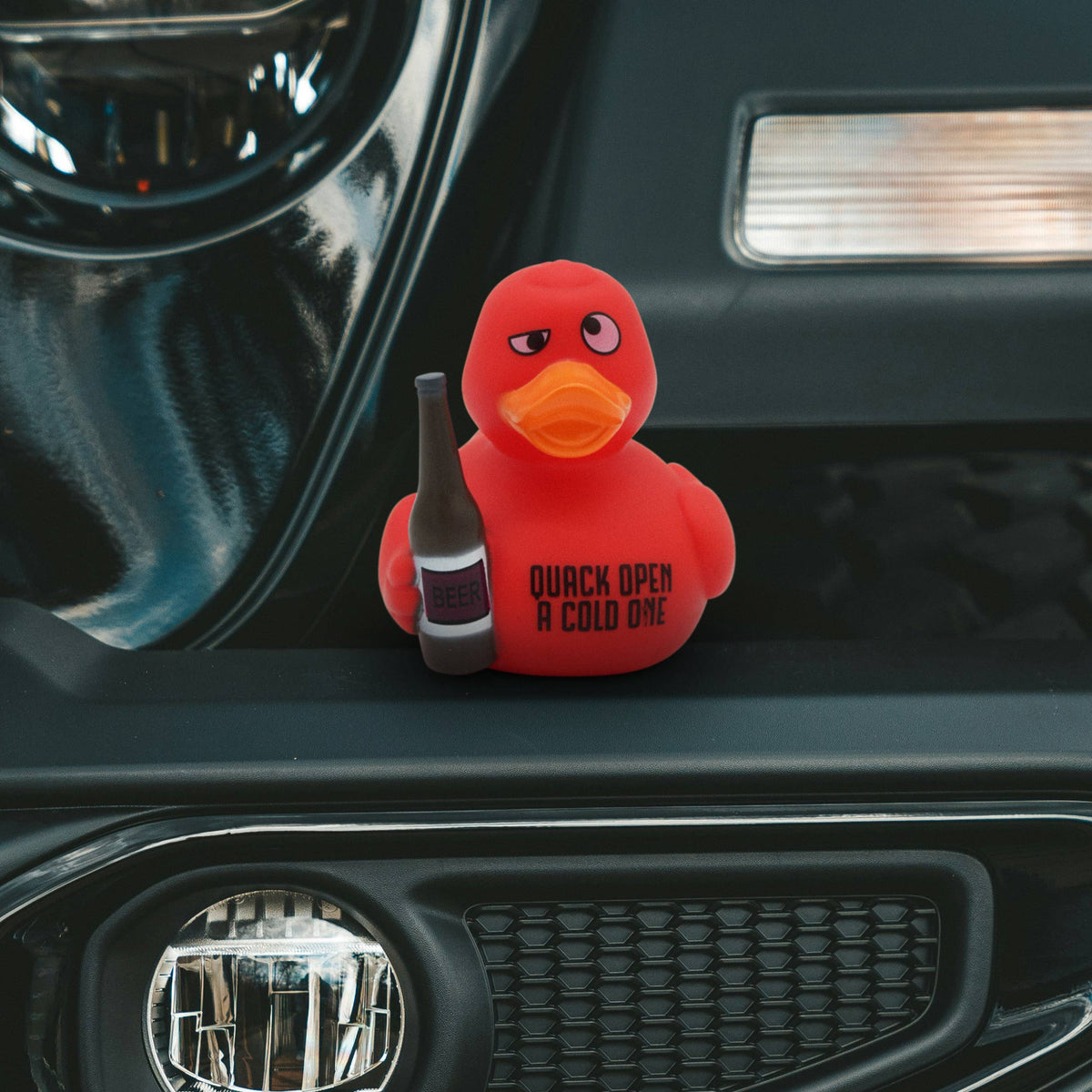 Mellow Monkey red rubber duck holding a beer bottle with Quack Open a Cold One text on a car dashboard